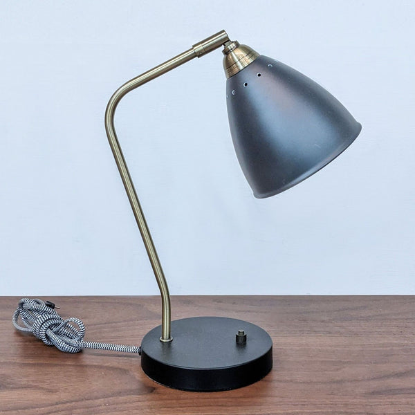 Reperch brand desk lamp with a gray shade and brass arm on a black base, viewed from the side.