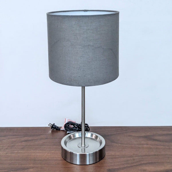 Reperch brand table lamp with grey shade and metallic base on a wooden surface.