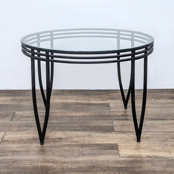 Reperch brand dining table with a round glass top and a structured metal base on a wooden floor.