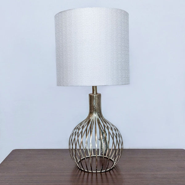 Reperch brand table lamp with a textured white shade and metallic cage-like base on a wooden surface.