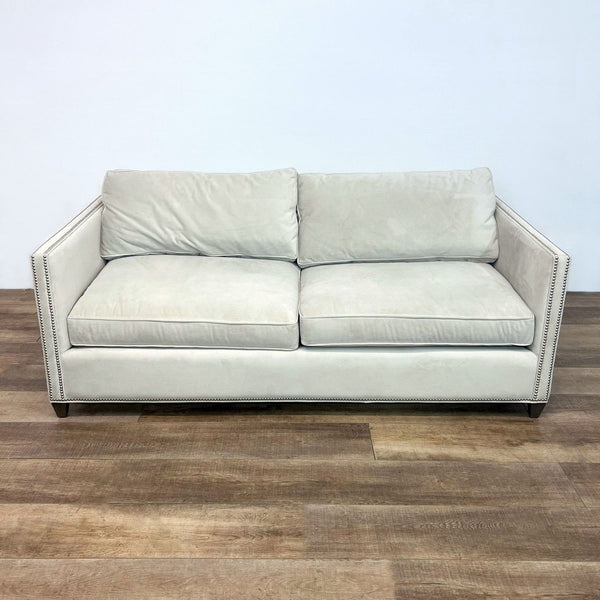 Alt text 1: Cream-colored Crate & Barrel compact sofa with nailhead trim and two cushions, set against a plain backdrop.