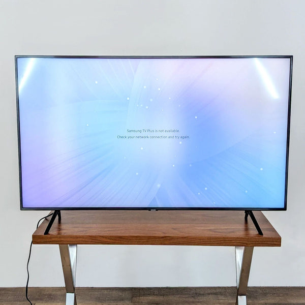 Samsung flat-screen TV displaying an error message on a wooden stand against a white wall.