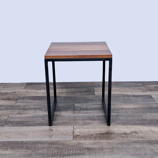 Reperch brand end table with a sleek metal base and a warm wooden top, on a wood-patterned floor.