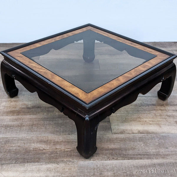 Reperch brand coffee table with burlwood frame and glass top, low profile on wooden flooring.