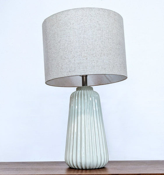Reperch brand table lamp with a textured grey lampshade and ribbed pale green base on a wooden surface.