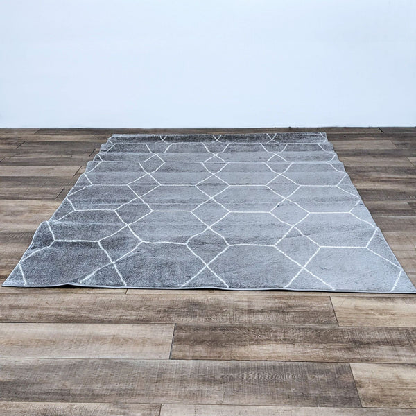 Alt text 1: A 6x9 Unique Loom Trellis Frieze area rug displayed on a wooden floor, featuring a grey polypropylene medium pile with a geometric pattern.