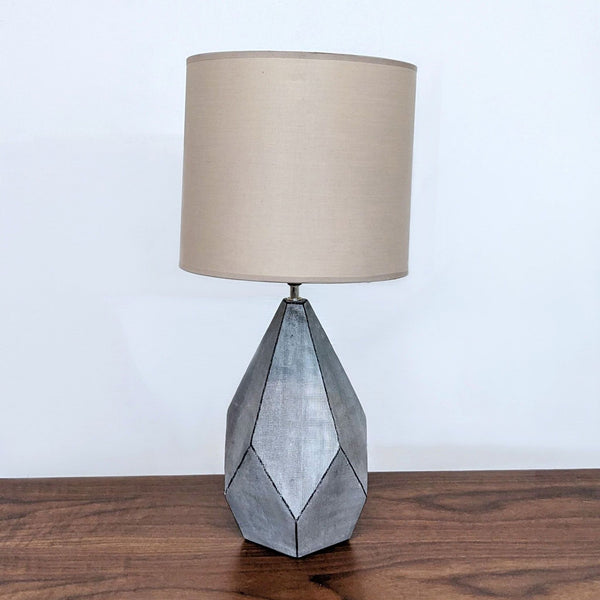 Reperch brand table lamp with a beige shade and geometric metal base on a wooden surface.