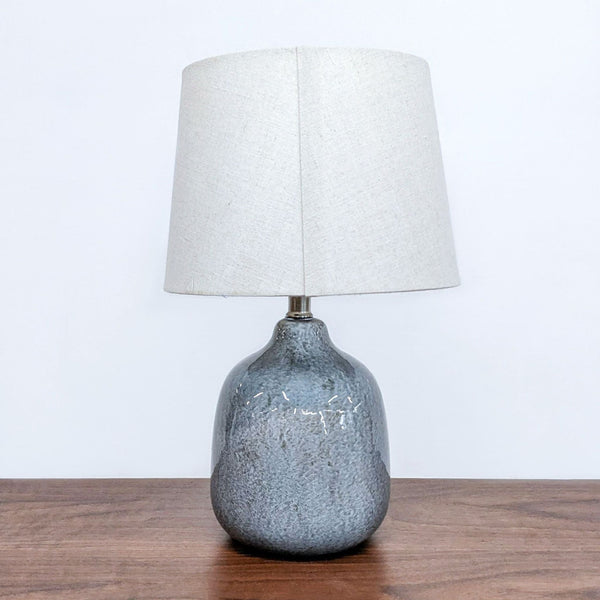 Reperch brand table lamp with textured grey base and white shade on wood surface.