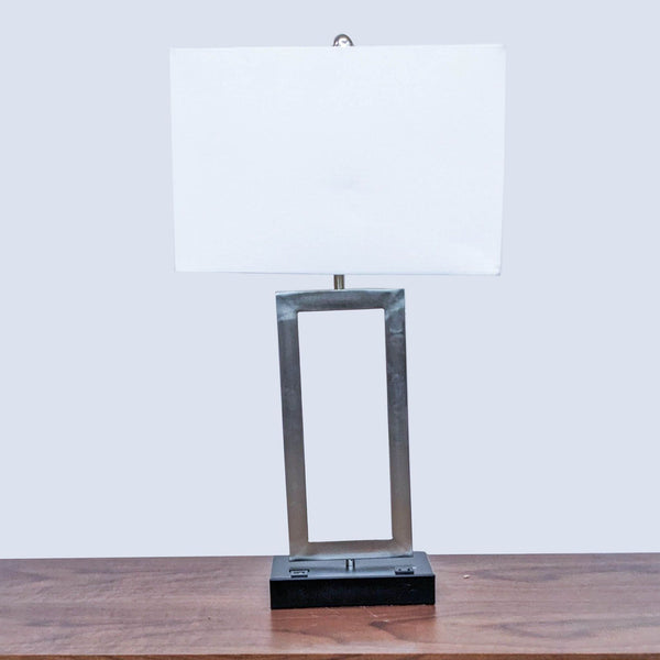 Rectangular white shade Reperch table lamp with a geometric metal base on a wooden surface.