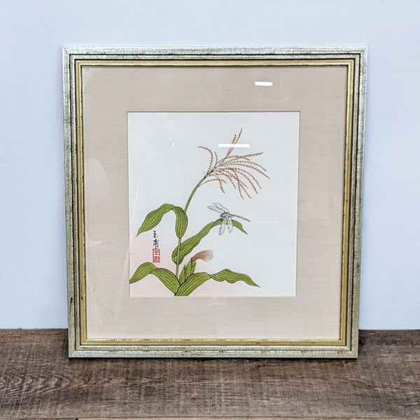 Botanical print with delicate plant and dragonfly, featuring Asian calligraphy, encased in a gold frame by Reperch.