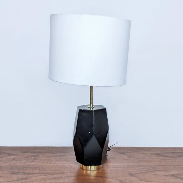 Reperch brand table lamp with geometric black base and white shade on a wooden surface.