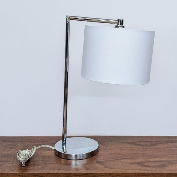 Reperch brand modern table lamp with white shade and sleek chrome base, positioned on a wooden surface.