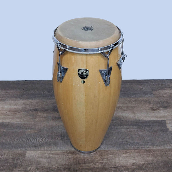 Alt text 1: A single Cosmic Percussion wooden conga drum with natural skin head and chrome hardware, stickered, against a wooden floor backdrop.