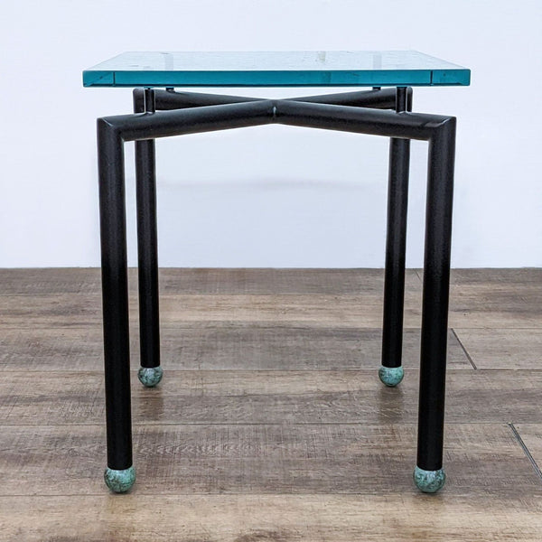 Reperch side table with a metal base and blue-tinted glass top, standing on a wooden floor.