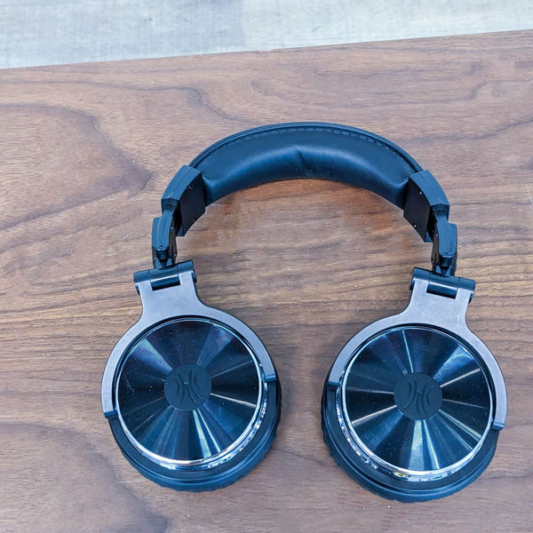 OneOdio DJ headphones with cushioned ear cups and a coiled cable on a wooden surface.