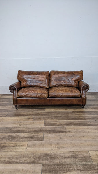 A traditional-style cognac leather loveseat with rolled arms and nailhead trim by Reperch.