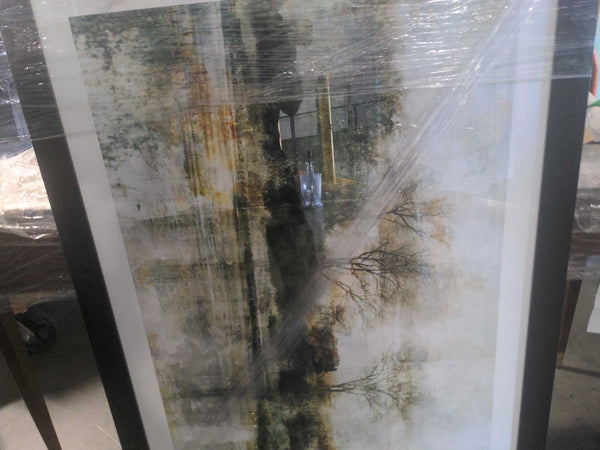 1. Framed landscape print with trees and water, partially wrapped in plastic with reflections and muted colors.  