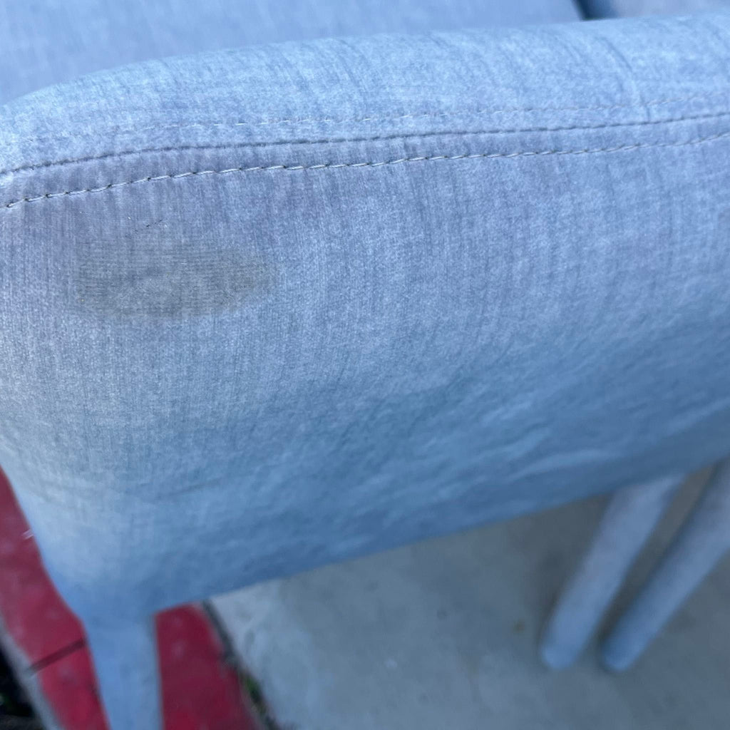 2. Close-up of the light blue fabric on a New Pacific Direct dining chair, showing minor discoloration.