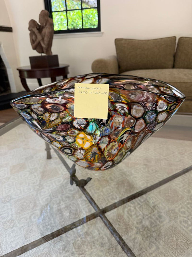 1. Colorful, abstract Venetian glass bowl with circular patterns, displayed on a glass table in a modern living room.
