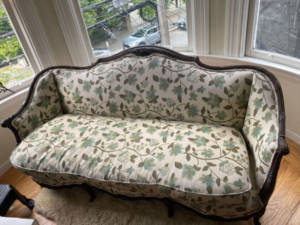 1. Vintage 3-seat sofa with floral upholstery and a curved dark wood frame, placed by bay windows.