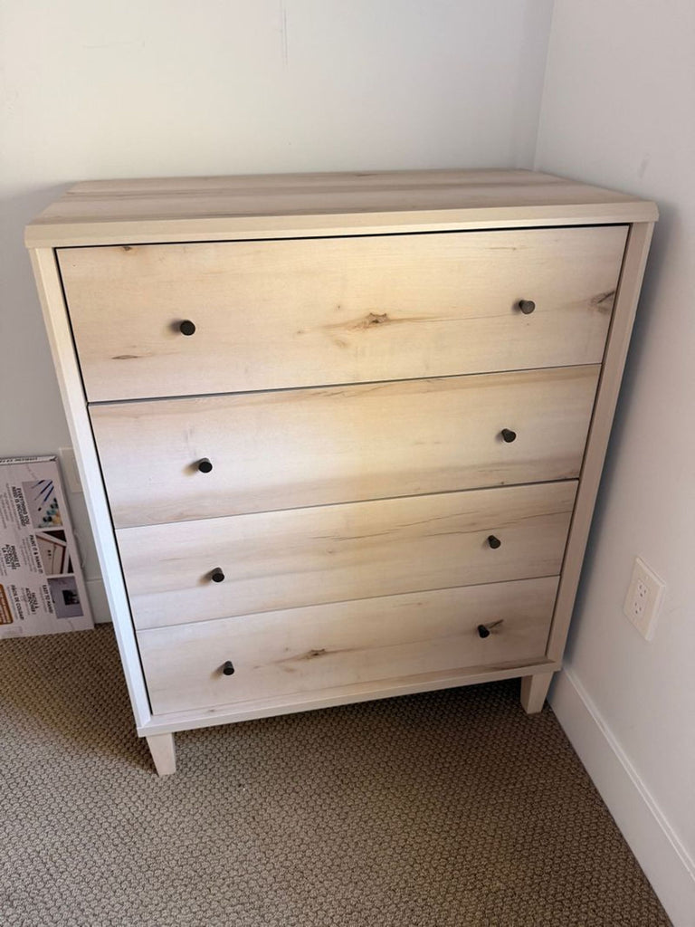 2. Minimalist three-drawer dresser with a natural wood finish and round black handles, against a white wall.