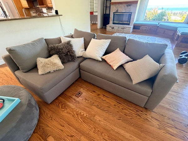 Gray Room & Board sectional sofa featuring a pull-out ottoman and hidden under-seat storage.