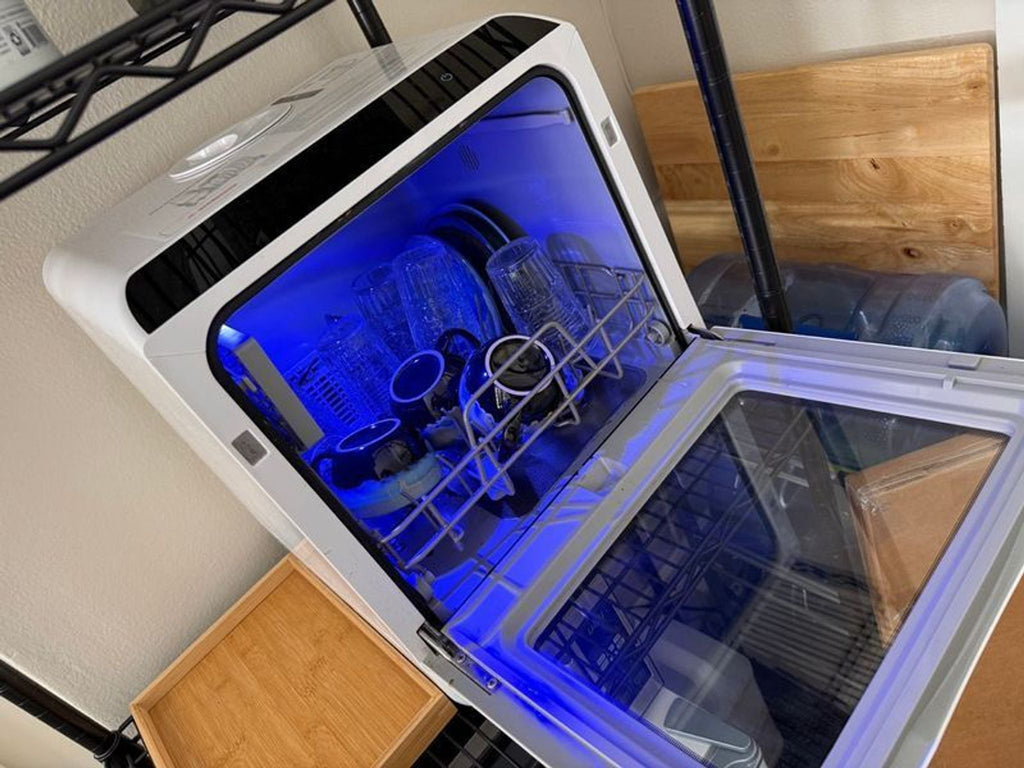 2. Small white NOVETE dishwasher with the front door closed, showing empty racks through a transparent window.