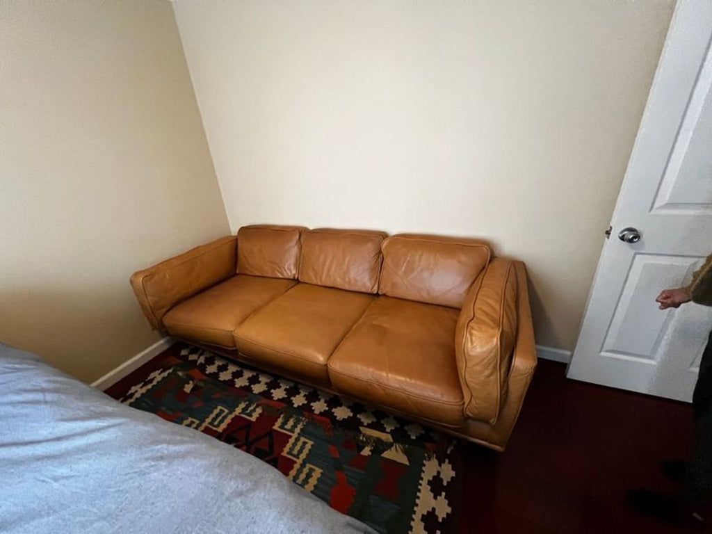 Tan 3-seat Article sofa placed against a light wall, with a patterned rug beneath.