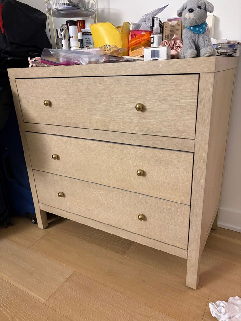 1. Light wood 3-drawer dresser by Butler Specialty Company, topped with toiletries and a plush toy, seen in a home setting.