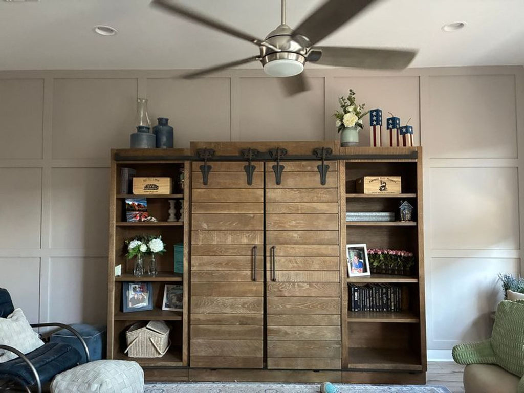 2. Arhaus entertainment center with open shelves featuring decor and barn-style cabinet doors closed.