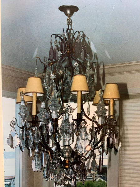 1. Ornate crystal chandelier with candle-shaped lights and small cream lampshades, hanging from a ceiling.  