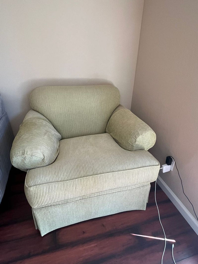 1. Light green corduroy lounge chair with rolled arms, positioned in the corner on dark wood floor.  