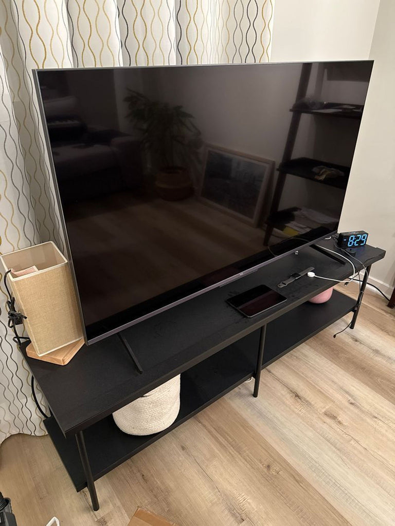 1. TCL R646 TV displayed on a modern TV stand, showcasing its sleek design in a living room setting.  
