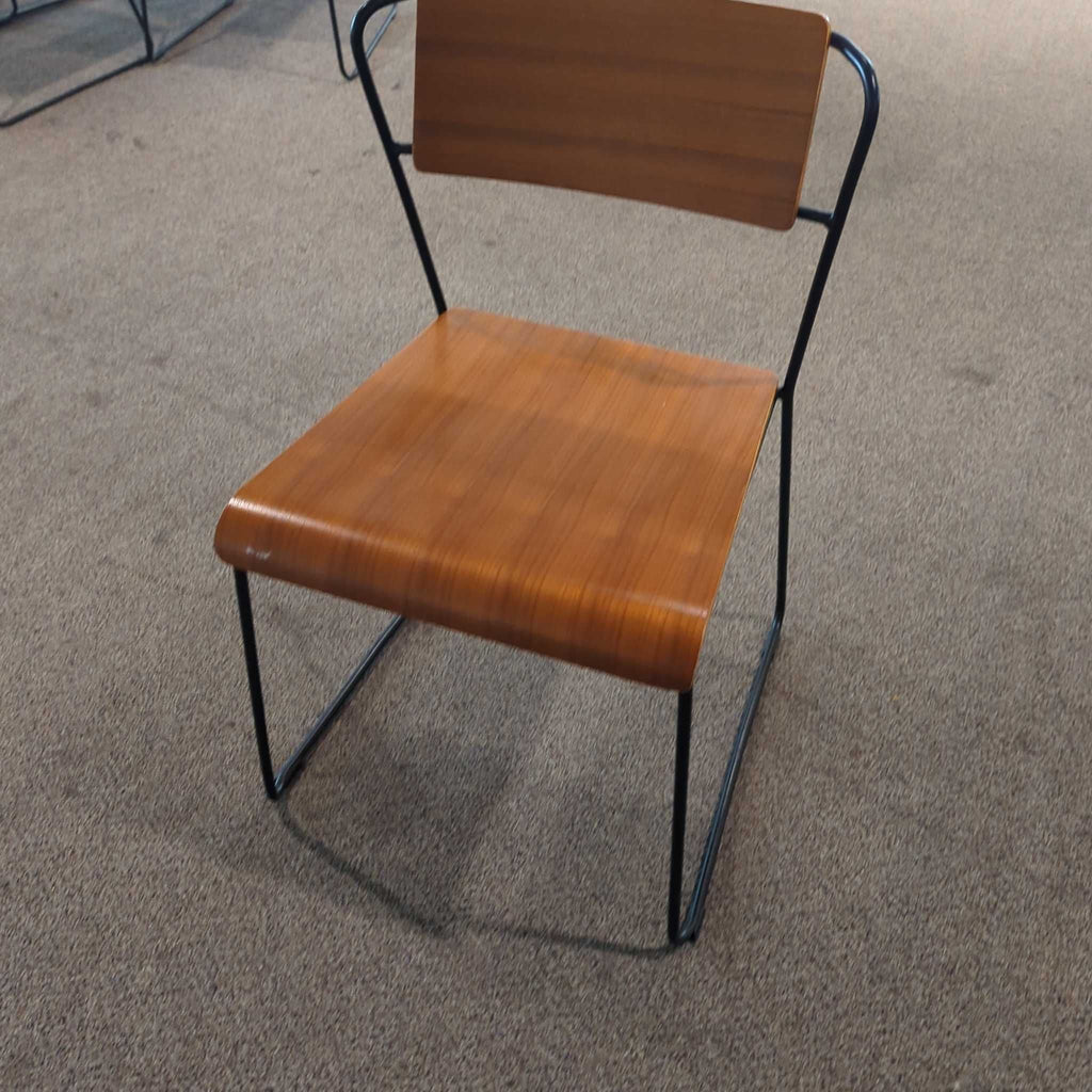 1. Modern dining chair by m.a.d. Furniture Design featuring a curved wood seat and metal frame on carpet.