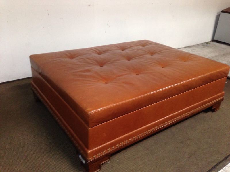 3. Brown leather Reperch coffee table with geometric form feet, tufted top, nailhead trim, and lift-up storage.