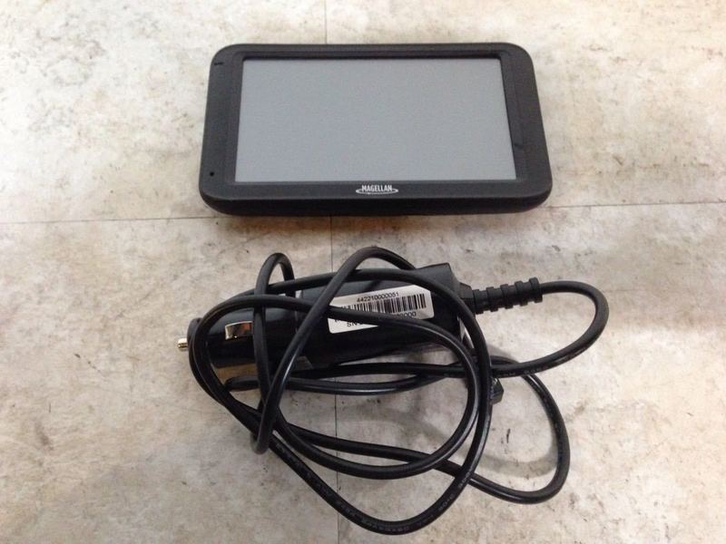 3. Magellan RoadMate GPS with accompanying power cord, both placed on a tiled floor.