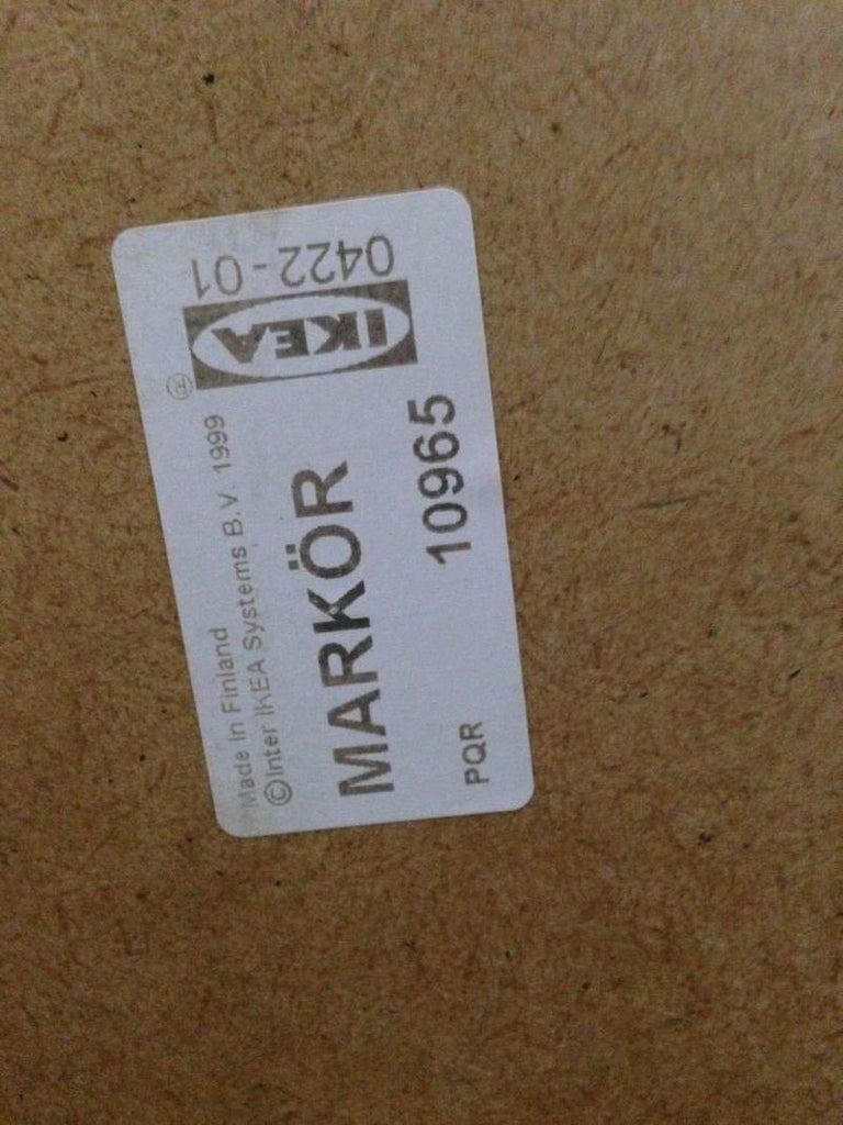 2. Close-up of IKEA sticker labeled "MARKÖR" on the plywood back of a bookshelf.