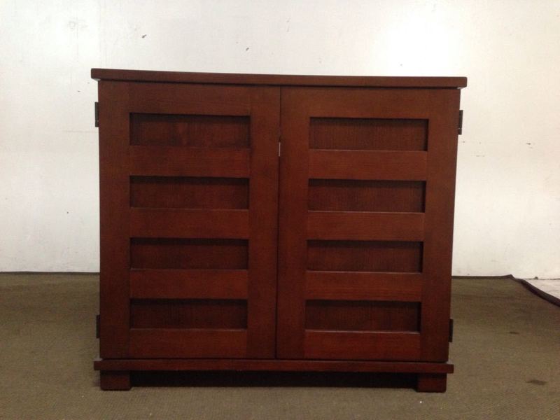 1. Dark wood entertainment center with two doors featuring geometric panels, designed for interior storage, closed view.