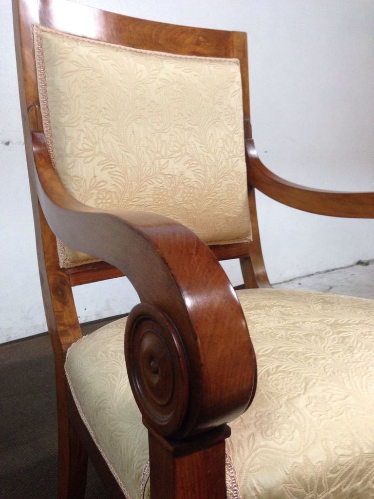 3. Close-up of a chair’s scrolled wooden arm and cream textured upholstery; Reperch brand chair.