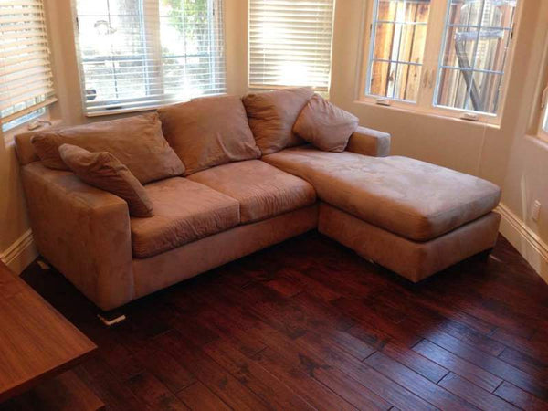 1. Reperch sofa with two throw pillows and wood feet, placed in a bright, windowed corner on hardwood floor.  