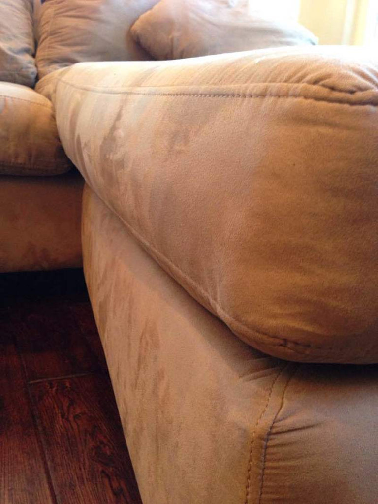 3. Close-up of a beige Reperch sofa’s suede fabric and stitched details, showing wood feet below.