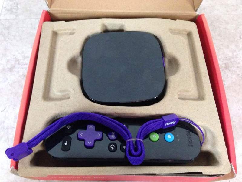 3. Unboxed Roku 2 XS streaming device and remote control with purple wrist strap inside original packaging.