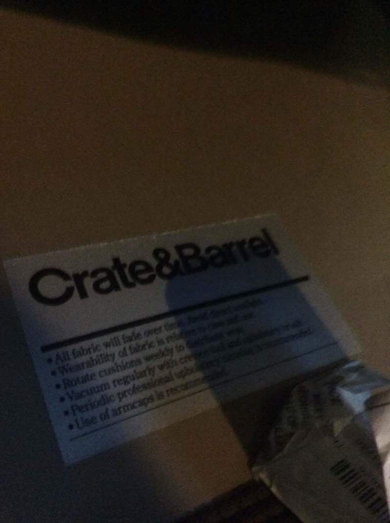2. Close-up of Crate & Barrel brand label with care instructions attached to sofa fabric.
