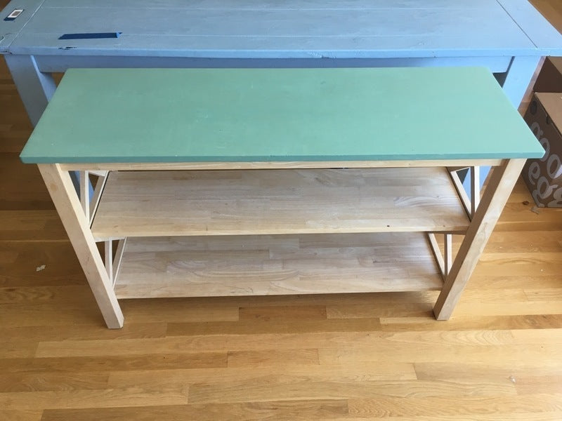 2. Modern Reperch bookshelf with a light green top and two spacious shelves, natural wood, crisscross side details.