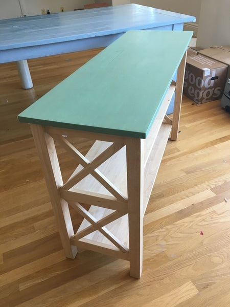 1. Reperch bookshelf with a mint green top and natural wood frame, featuring two open shelves and X-side accents.