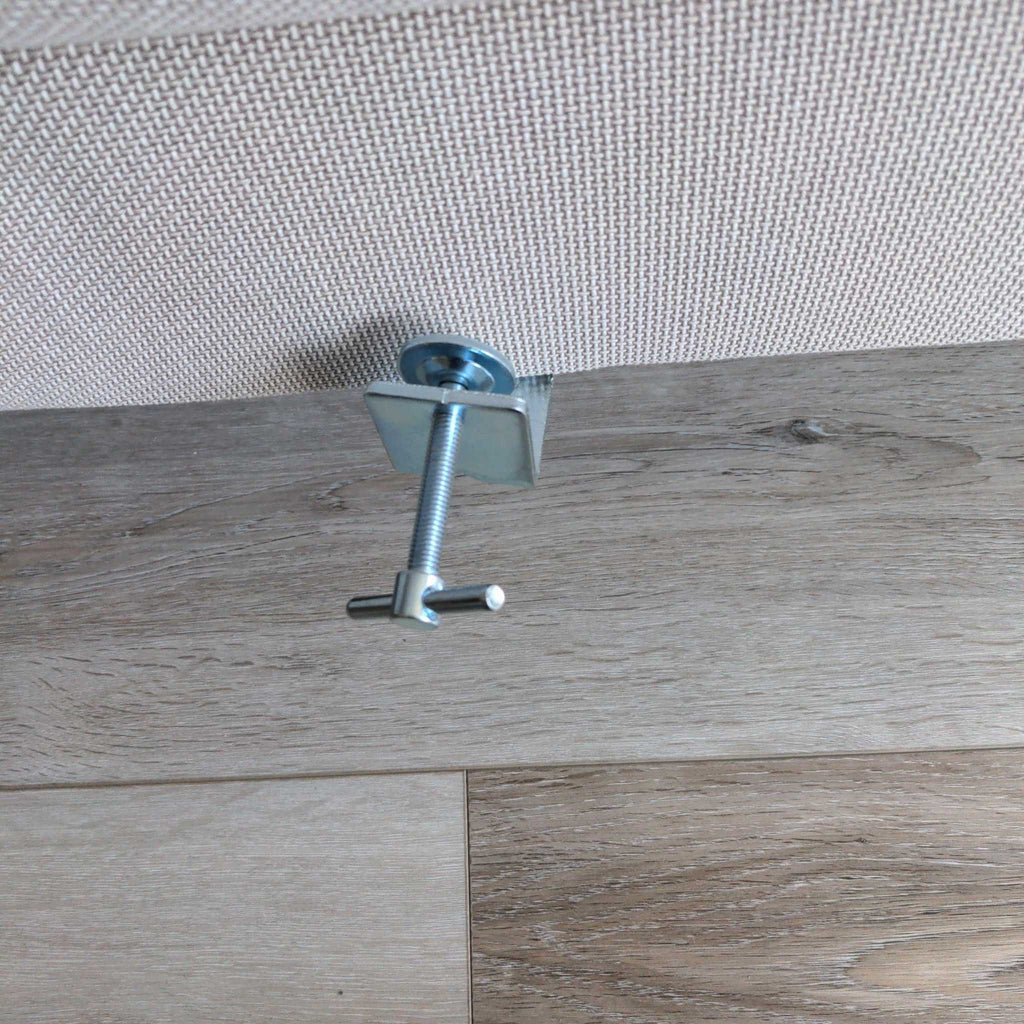 2. Detailed view of a metal connector attached to the base of a sectional sofa on wood flooring.
