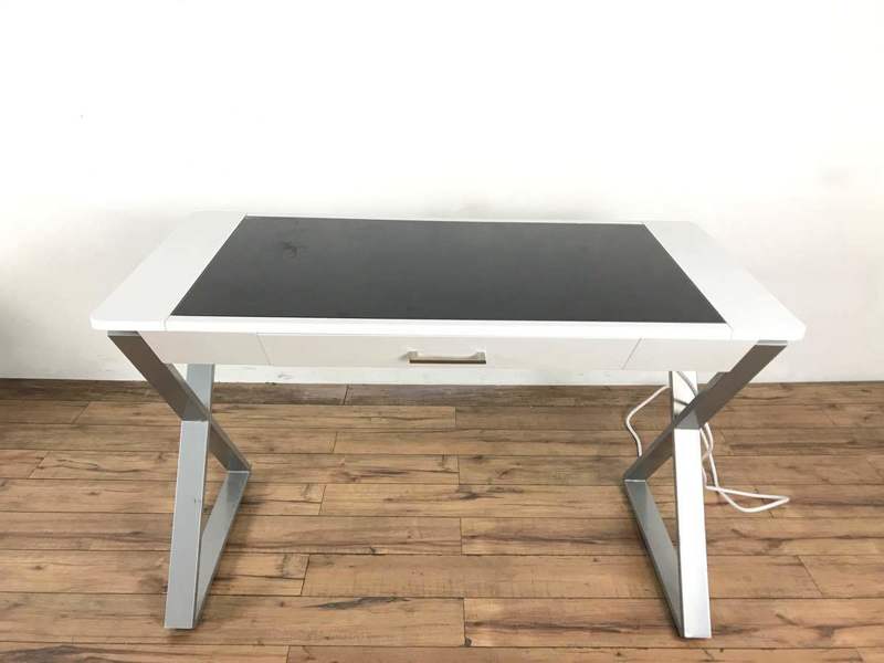 1. Modern Reperch desk with X-shaped metal legs, single drawer, and black top, designed for an office space.
