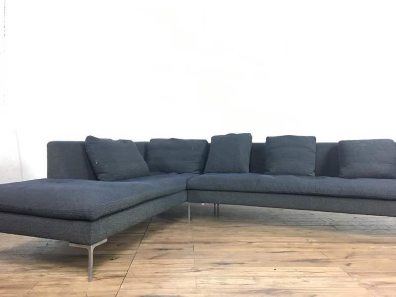 Dark gray sectional sofa with metal legs by B&B Italia, shown in a bright room with wood floors.  