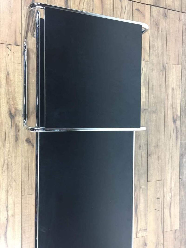 3. Top-down view of a Knoll coffee table, two black rectangular surfaces with sleek chrome frames on a wood floor.