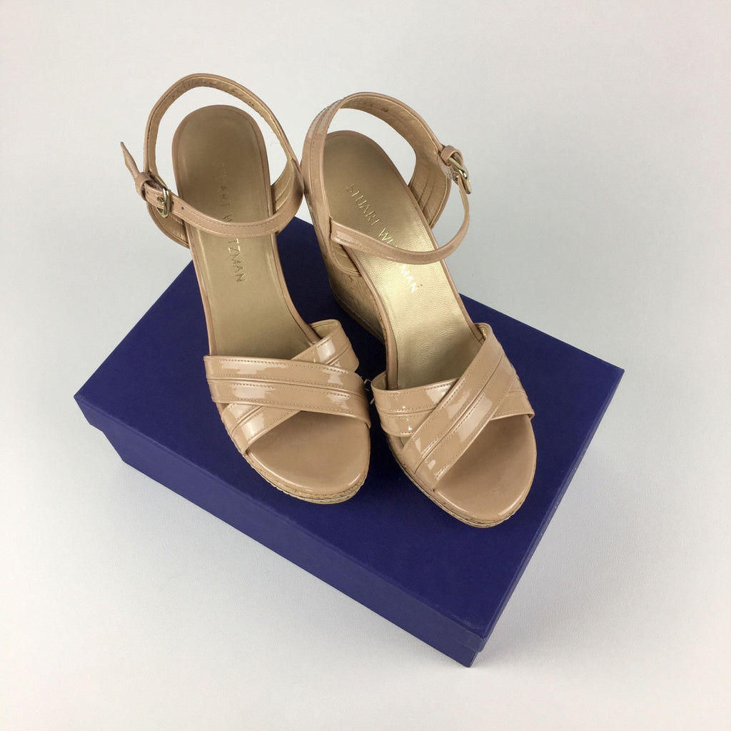 Stuart Weitzman nude patent leather wedges on a blue box.